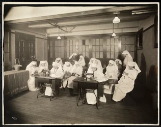 Femmes portant des blouses blanches, dans un cours de couture, probablement pendant ou en lien avec la Première Guerre mondiale, New York, c.1920